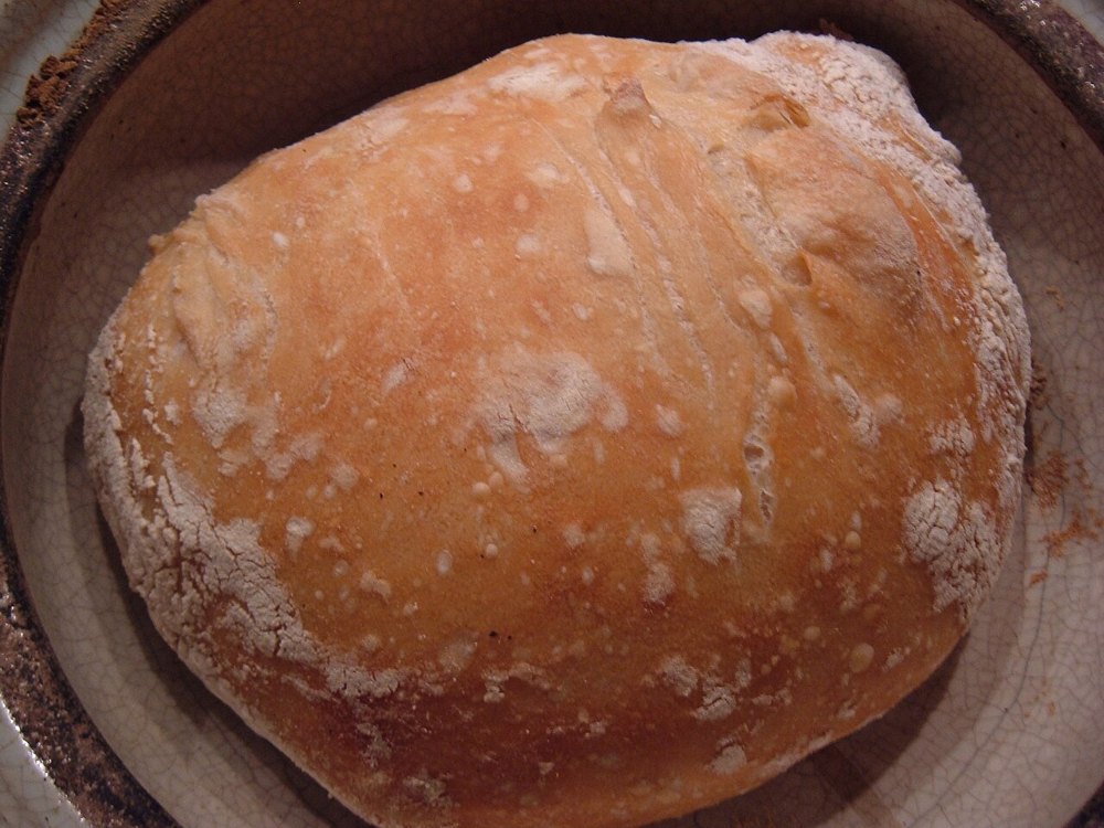 Runder goldbrauner No-Knead-Brotlaib mit bemehlter knuspriger Kruste