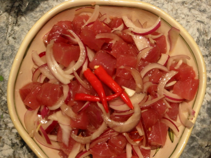 Schüssel mit rohen Ahi-Thunfischwürfeln, roten Zwiebelringen und roten Chilischoten