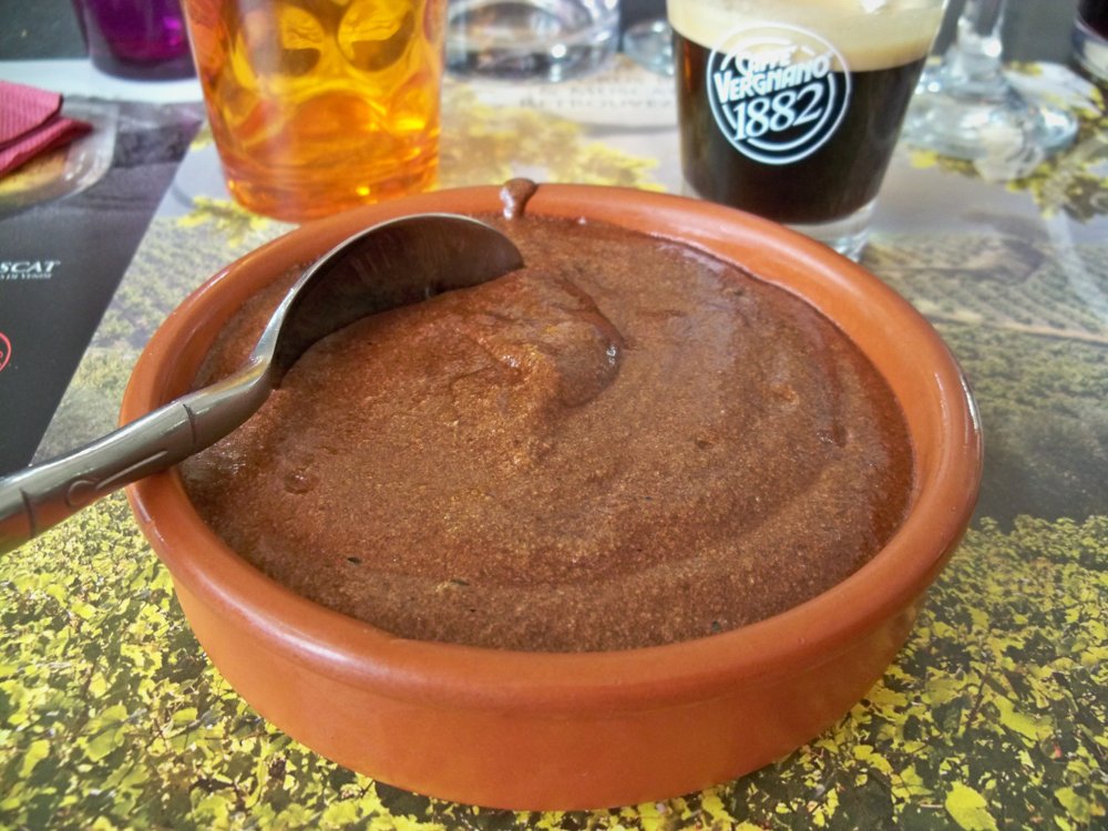 Dunkle Mousse au chocolat in einer Tonschale mit Löffel