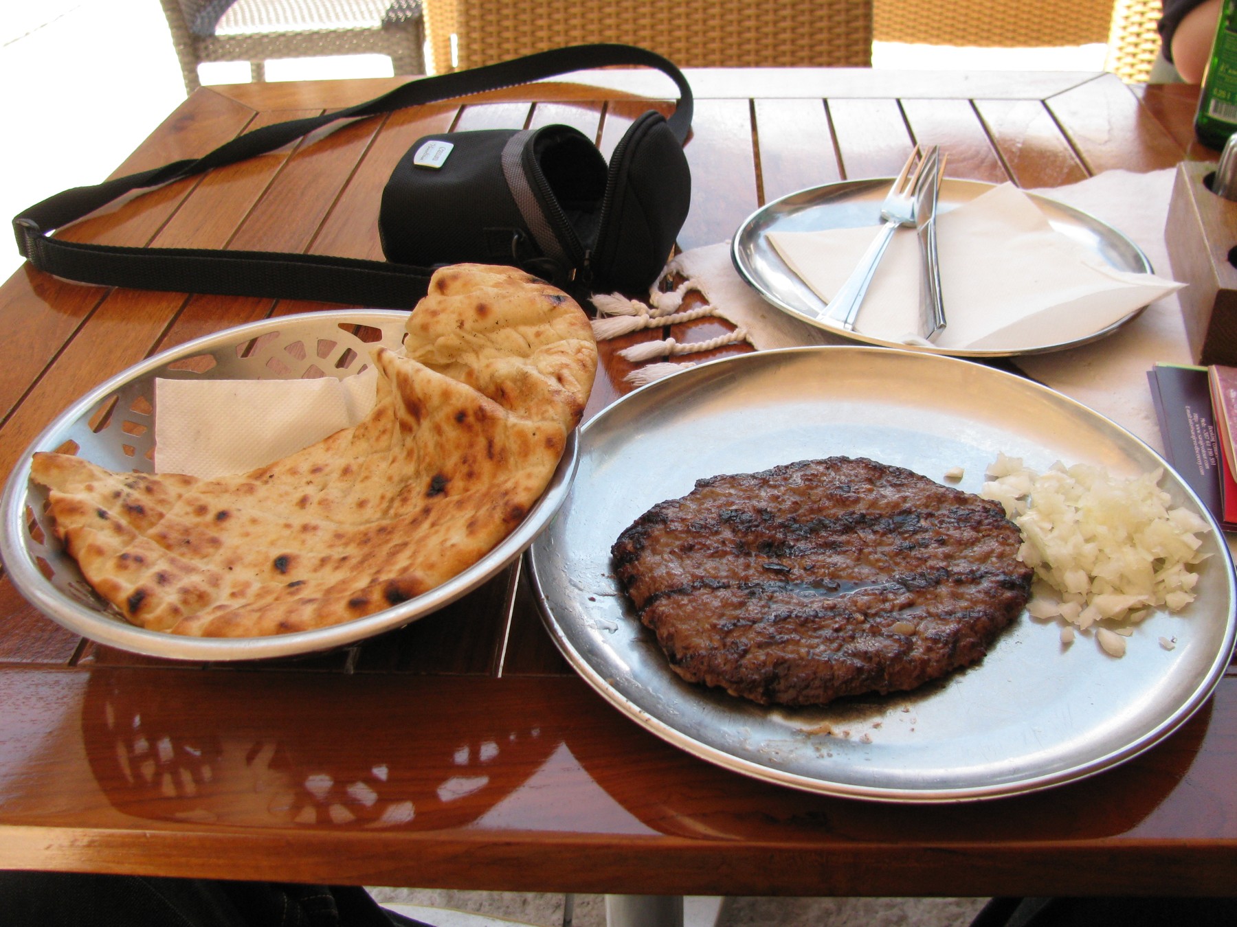 Gegrillte Pljeskavica mit angebratener Kruste, serviert mit Zwiebeln