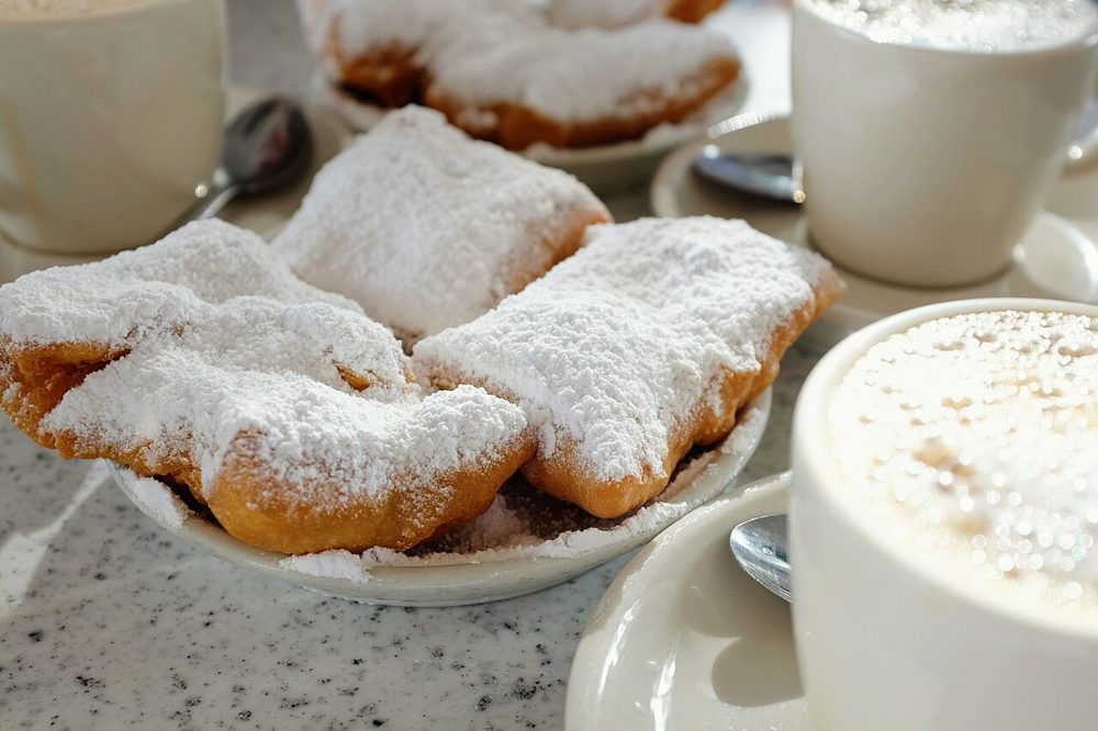 Beignets mit Puderzucker neben Café au Lait