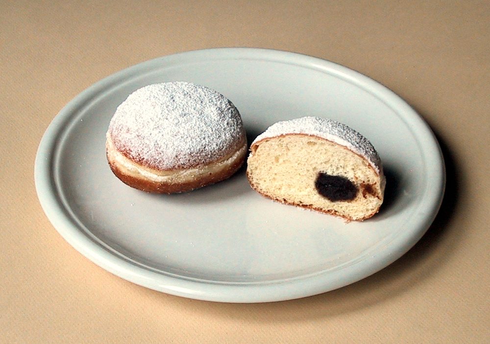 Zwei Berliner mit Puderzucker, einer aufgeschnitten mit Marmelade