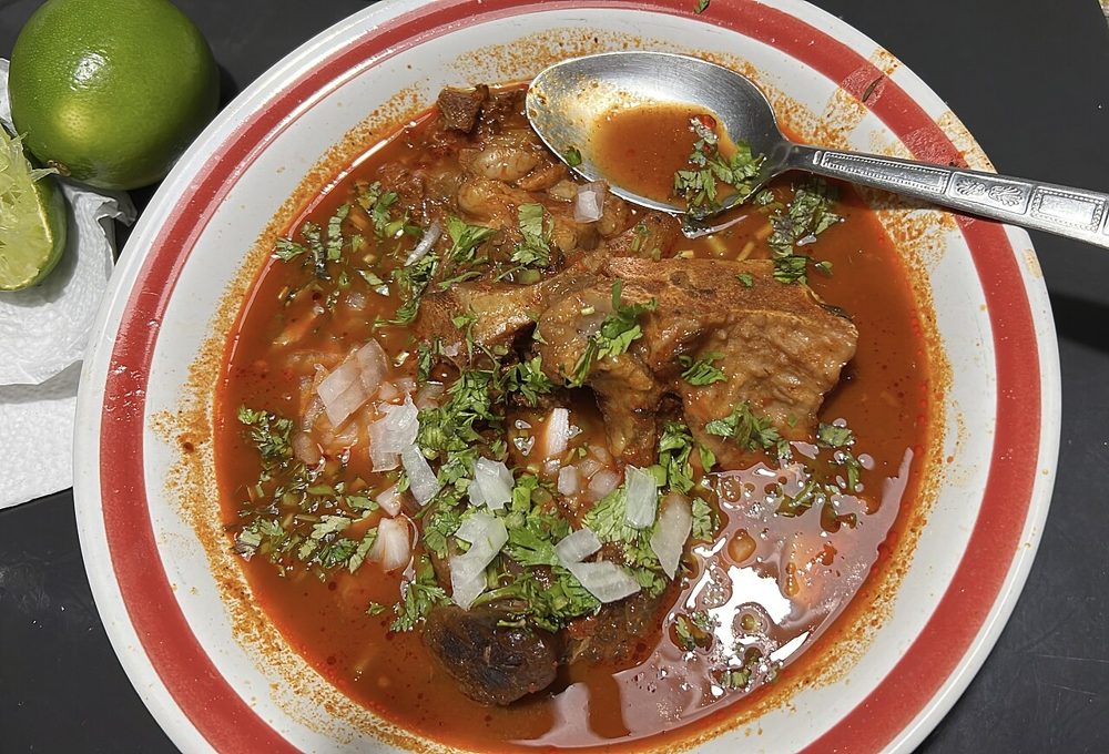 Schale mit Birria in roter Brühe, Zwiebel und Koriander