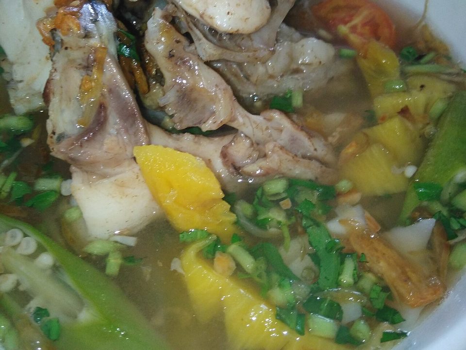Schüssel saure Suppe mit Fisch, Ananas, Okra und Kräutern