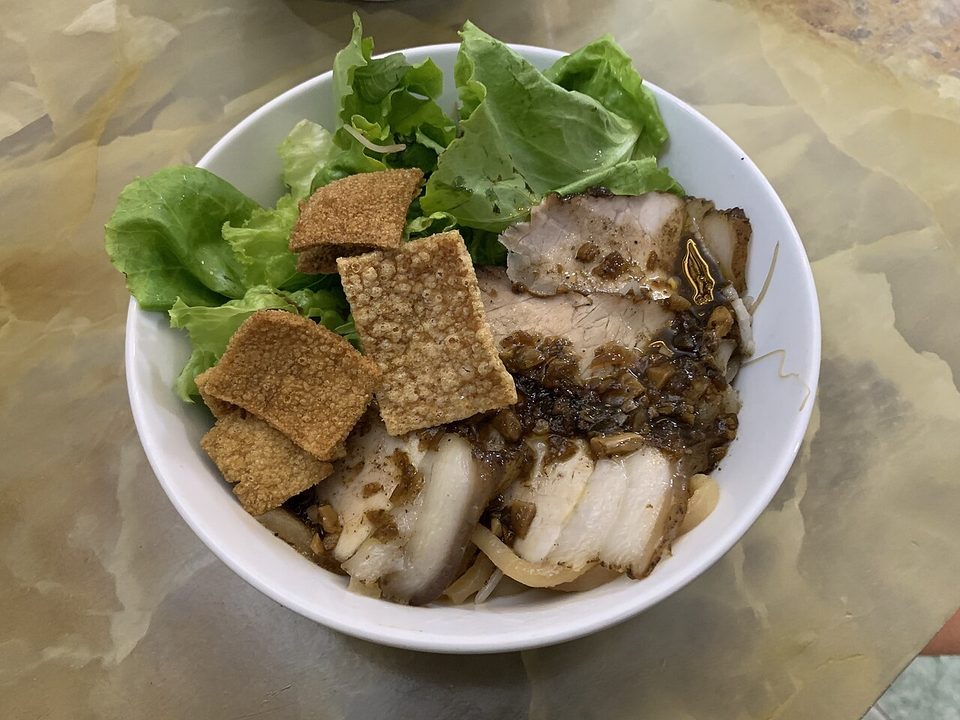 Schale Cao lầu mit Schweinefleischscheiben, knusprigen Crackern und Salat