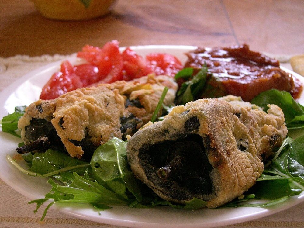Zwei frittierte gefüllte Poblano-Chilis auf Salat mit Tomatensauce