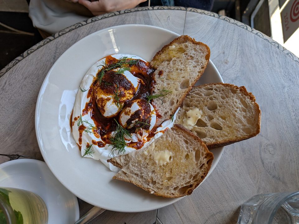 Zwei pochierte Eier auf Knoblauchjoghurt mit roter Chili-Butter in einer Schale