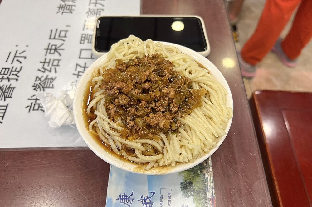 Weizennudeln mit gebratenem Hackfleisch und eingelegtem Gemüse in einer Schale