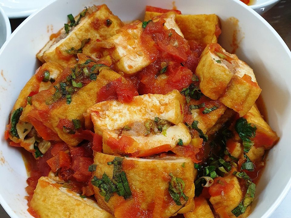 Schüssel mit gebratenen Tofustücken in roter Tomatensauce mit Kräutern