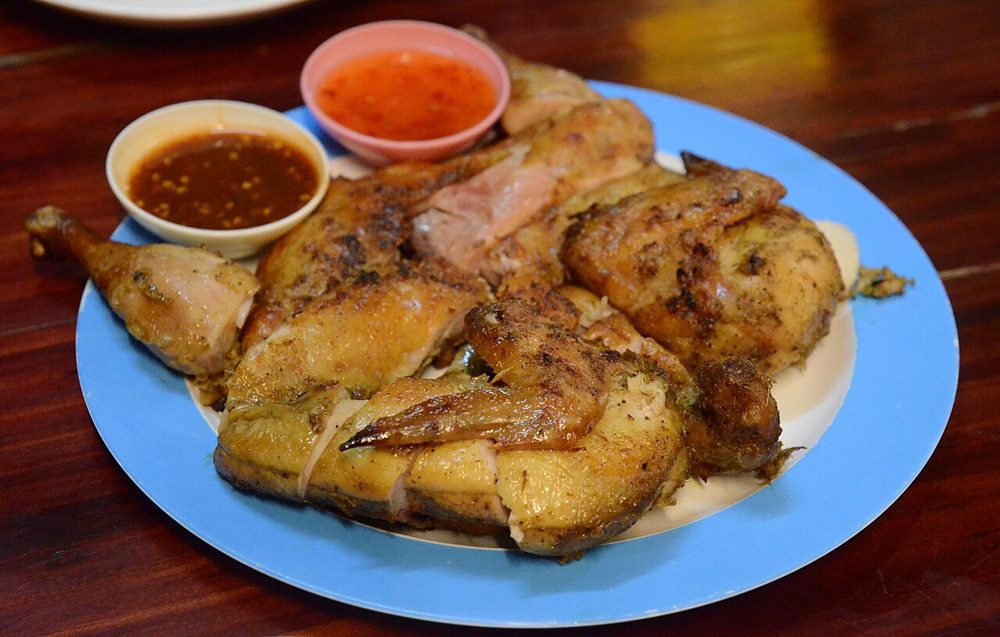 Gegrilltes Gai Yang mit Dip auf einem blauen Teller