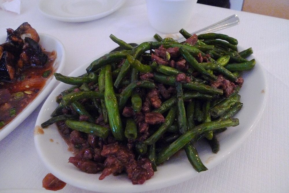 Grüne Bohnen mit roten Chilis auf einer bunten Platte