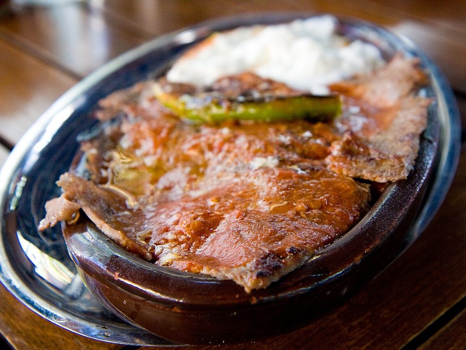 İskender Kebap in einer Metallpfanne mit Tomatensauce, Joghurt und Spitzpaprika