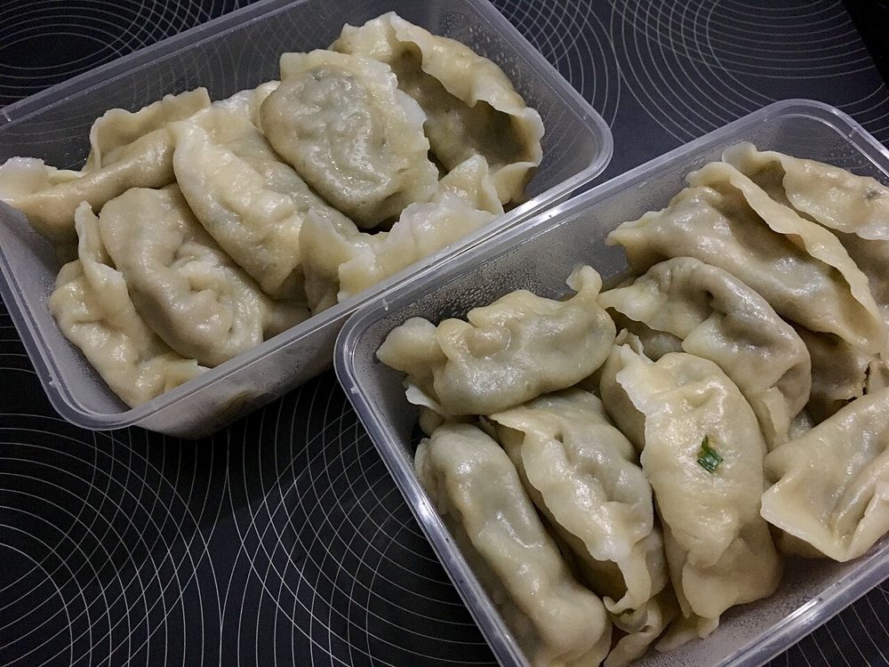 Teller gekochter Jiaozi mit einem Schälchen Dip