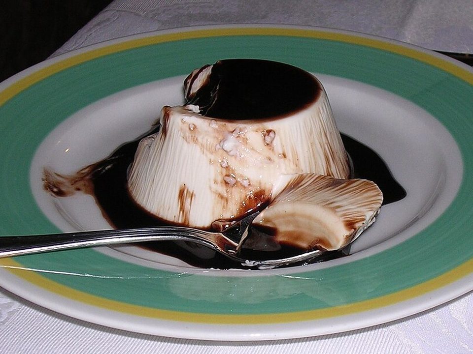 Gestürzte Panna cotta mit Karamellsauce und Beeren auf einem Teller