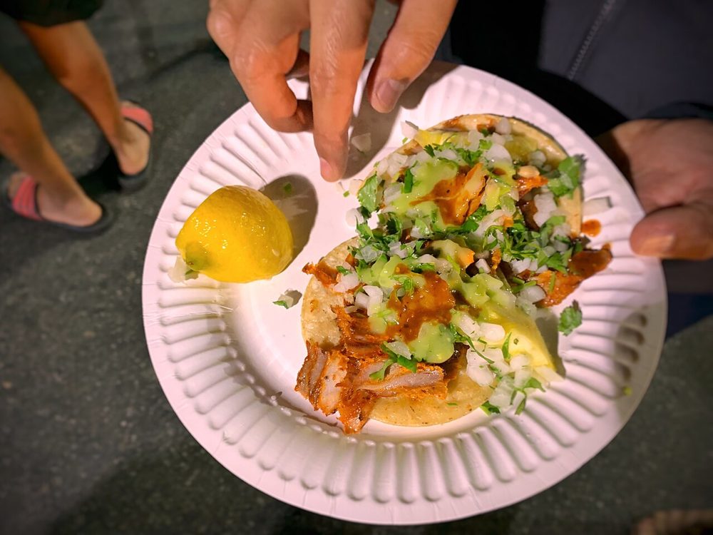 Tacos al pastor mit Koriander und Zwiebel auf einem Pappteller