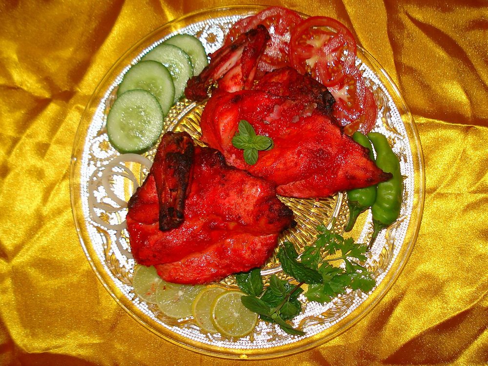 Rot marinierte Tandoori-Hähnchenstücke mit Gurke und Zitrone