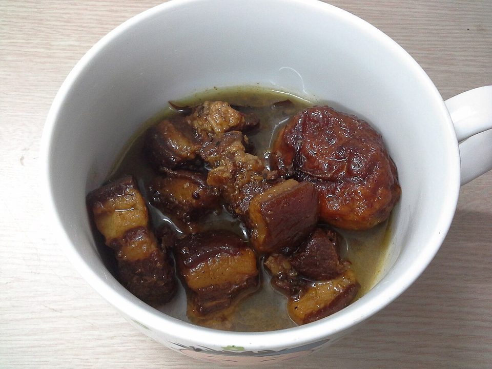 Tasse mit dunkel geschmortem Schweinebauch und braunem Ei