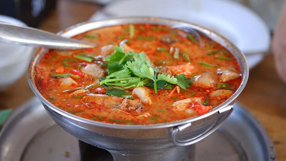 Rote Tom-Yum-Suppe mit Garnelen in einem Metallgefäß